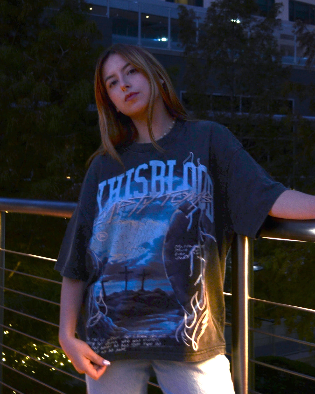 5'1" Female wearing a graphic t-shirt with text and design, standing outdoors at night.